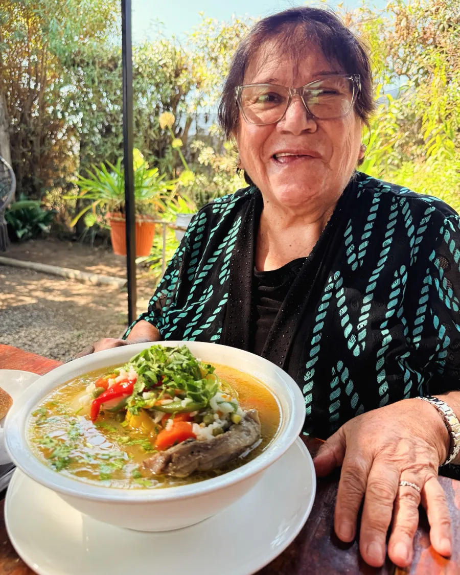 Elena Antivilo, mamá de Yanko, sonriendo frente a un plato de cazuela