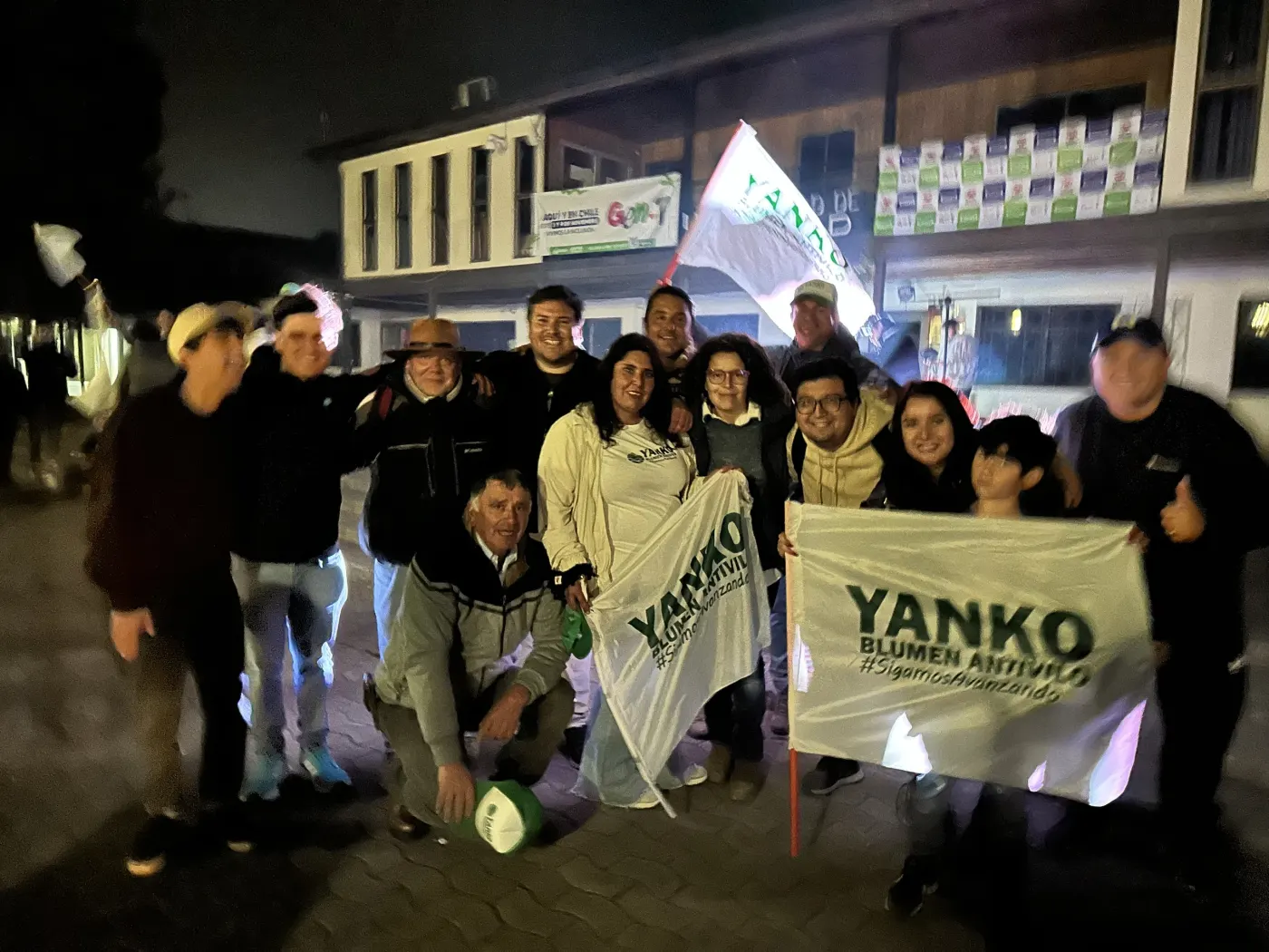 Yanko con un grupo de vecinos y banderas de noche en Navidad