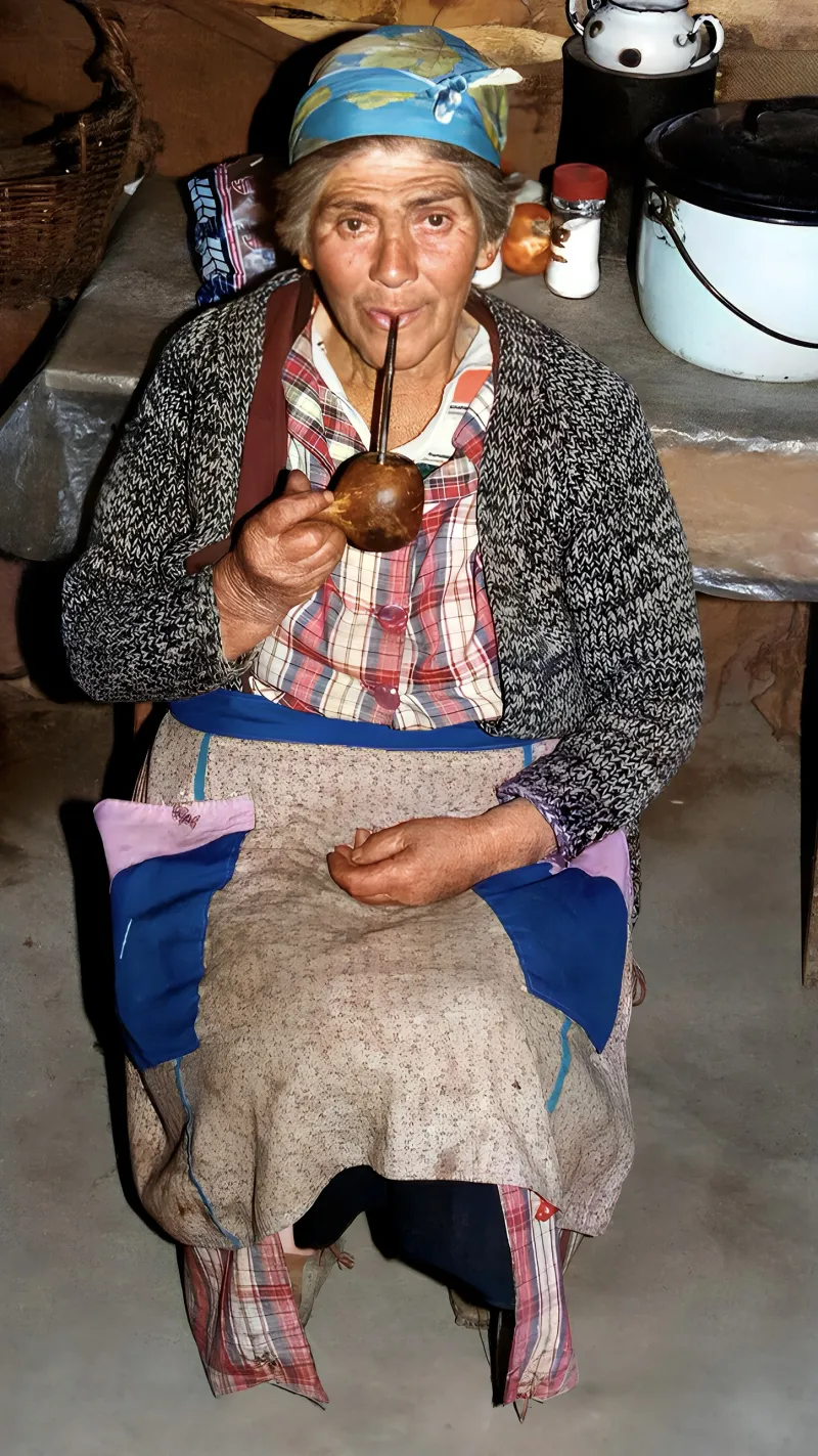 Fotografía antigua de Idelia Armijo, abuela de Yanko, tomando mate en una cocina de campo